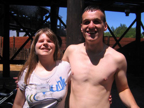 Eine junge Frau und ein junger Mann, Arm in Arm uns anlachend.