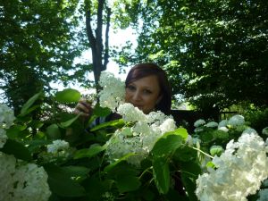 Eine Frau, inmitten vieler grüner Büsche und Bäume 