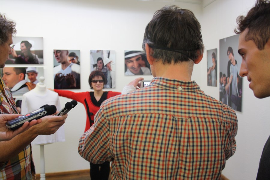 Ein Mann mit verbunden Augen fotografiert die Frau im roten Pullover.
