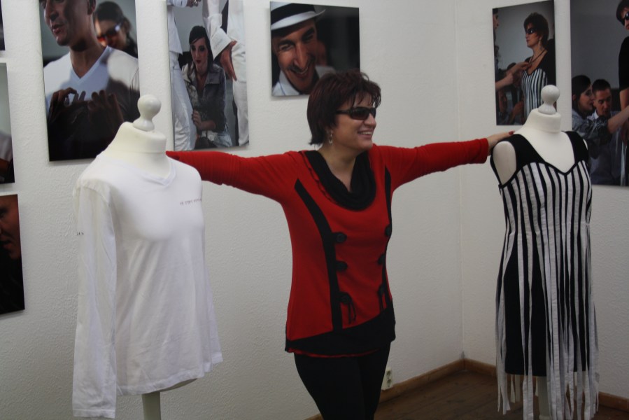 Eine Frau im roten Pullover steht in der Ausstellung "Die Schönheit der Blinden". Ihre ausgestreckten Arme berühren zwei Schneiderpuppen.