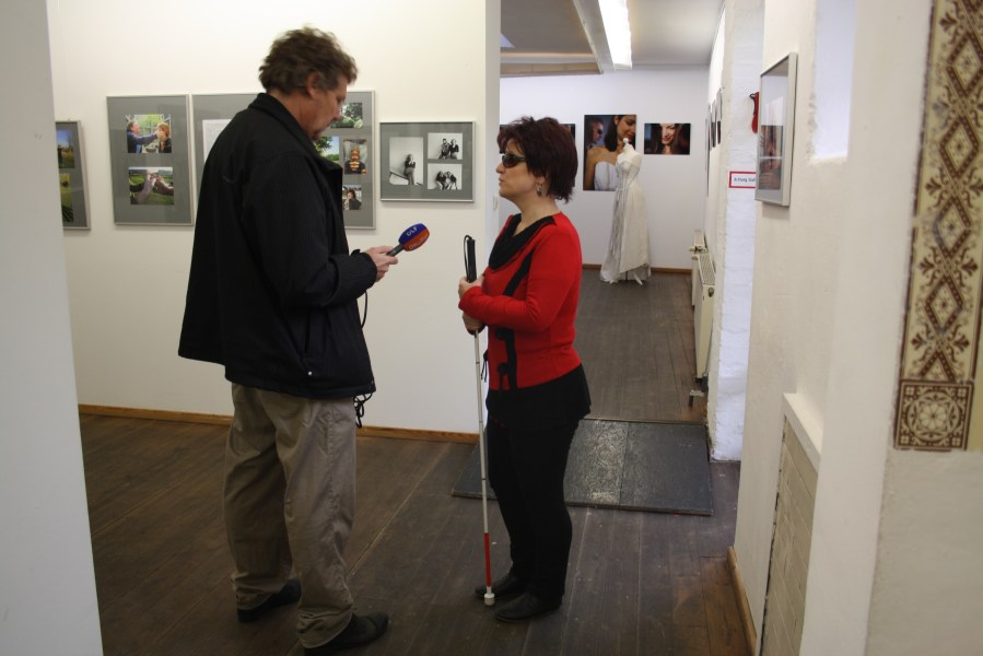 Ein Reporter hält einer Frau mit Langstock ein Mikro entgegen