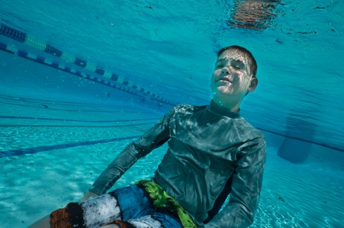 Auf dem Boden eines Weimming Pools sitzender Junge