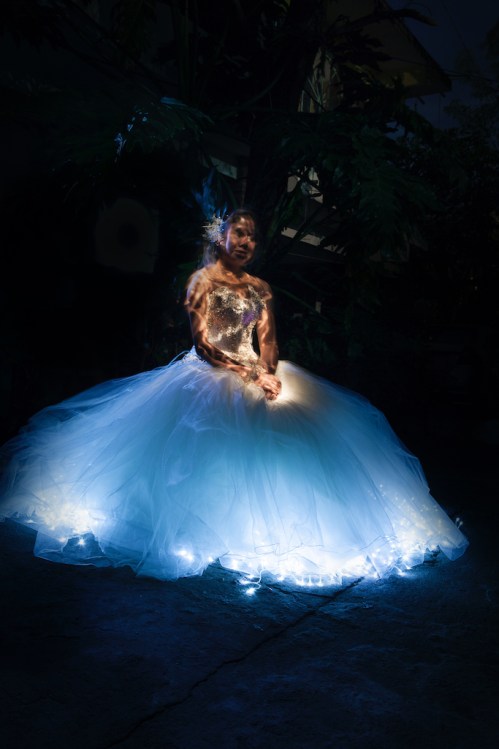 Junge Frau in einem ausladenden, erleuchtetem Ballkleid
